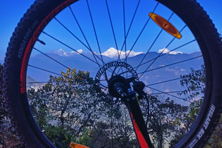 Creative frame of the stunning Mt Kanchenjunga mountain landscape using the wheel of a mountain bike, suggesting an adventure cycling expedition